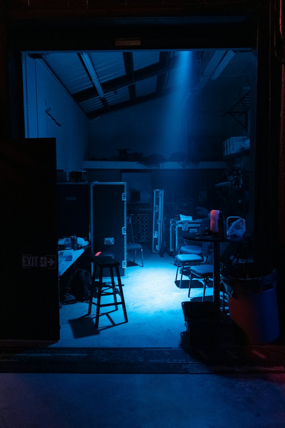 Una luce blu illumina l'attrezzatura in un magazzino disordinato.