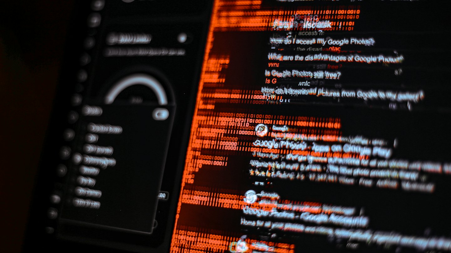 Schermo digitale mostra dati frammentati e codice binario arancione.