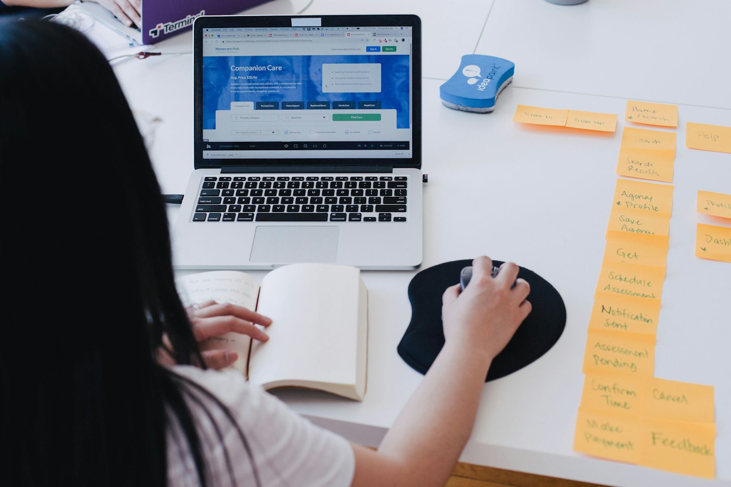 Persona che lavora al computer portatile con post-it sulla scrivania.